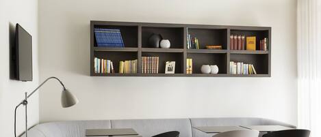 A modern living room with a grey sofa, black and white chairs, a coffee table, and a bookshelf with books and decorative items.