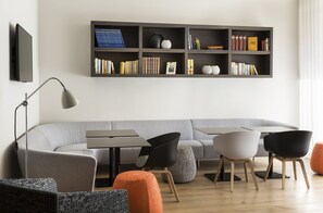 Relax in this stylish living room with a sofa, chair, and ottoman, featuring a flat-screen TV and bookshelf.
