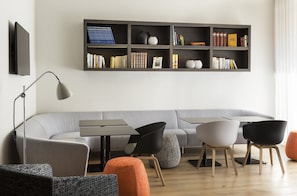 Relax in this stylish living room with a sofa, chair, and ottoman, featuring a flat-screen TV and bookshelf.