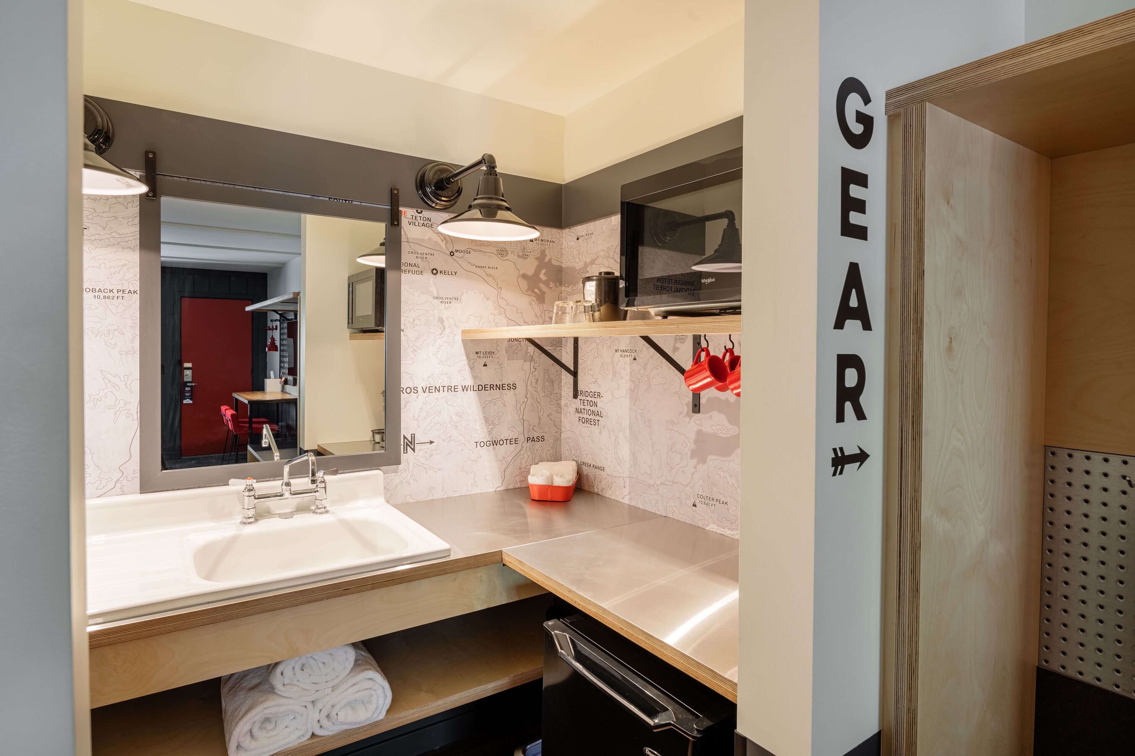 A modern bathroom with a large mirror, a sink, and a towel rack.