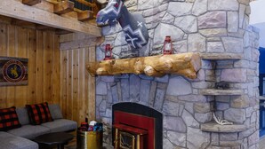 A rustic interior with a stone fireplace, wooden beams, a mounted deer head, and a cozy seating area. - Mountain Modern Jackson Hole (Jackson)
