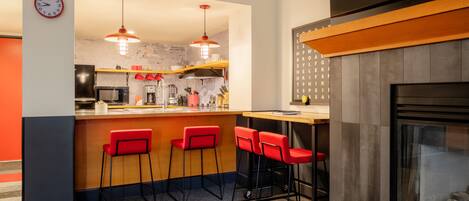 Une cuisine moderne avec un coin bar, des tabourets de bar rouges et une horloge au mur.