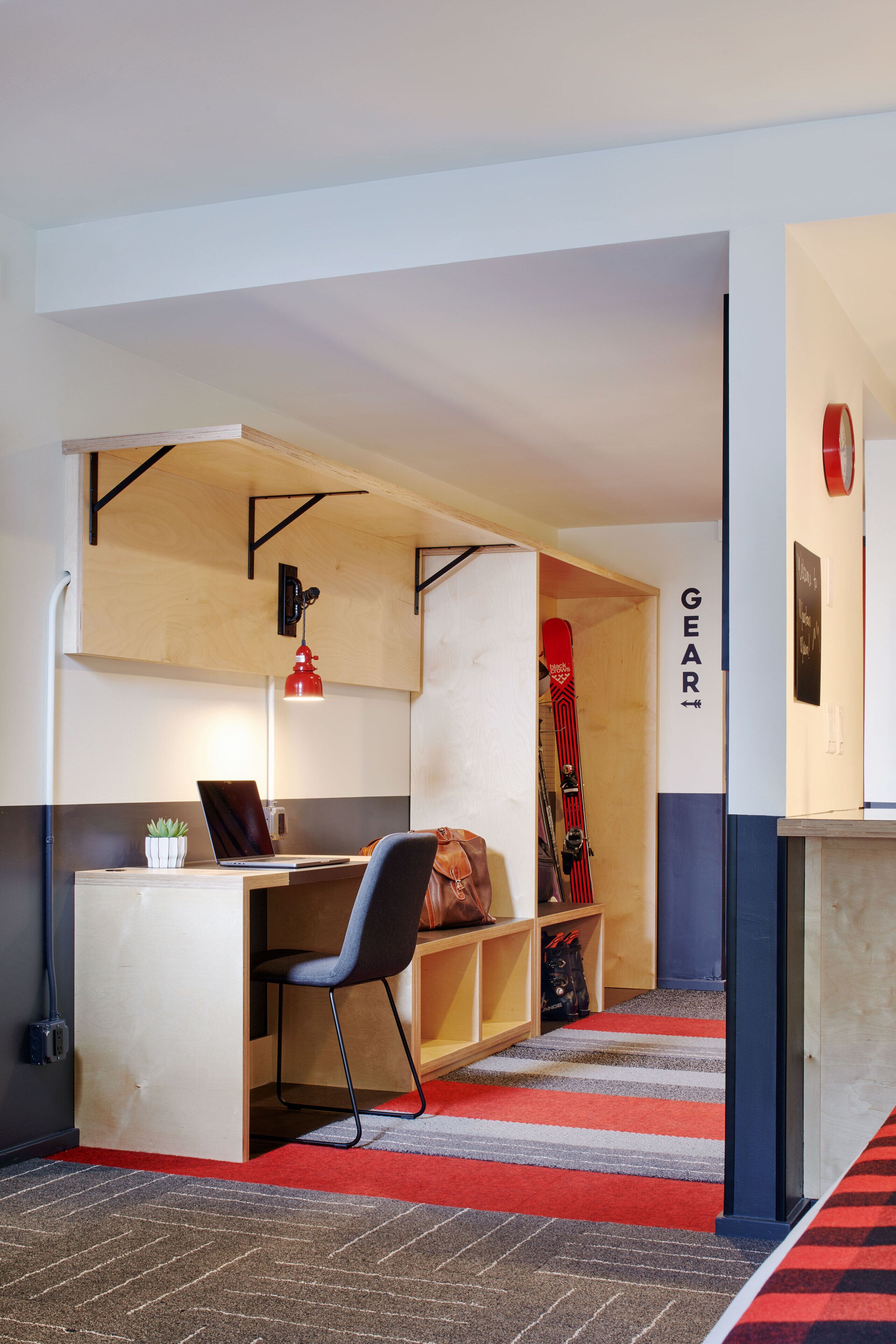 A compact room with a desk, chair, and a red carpeted area.