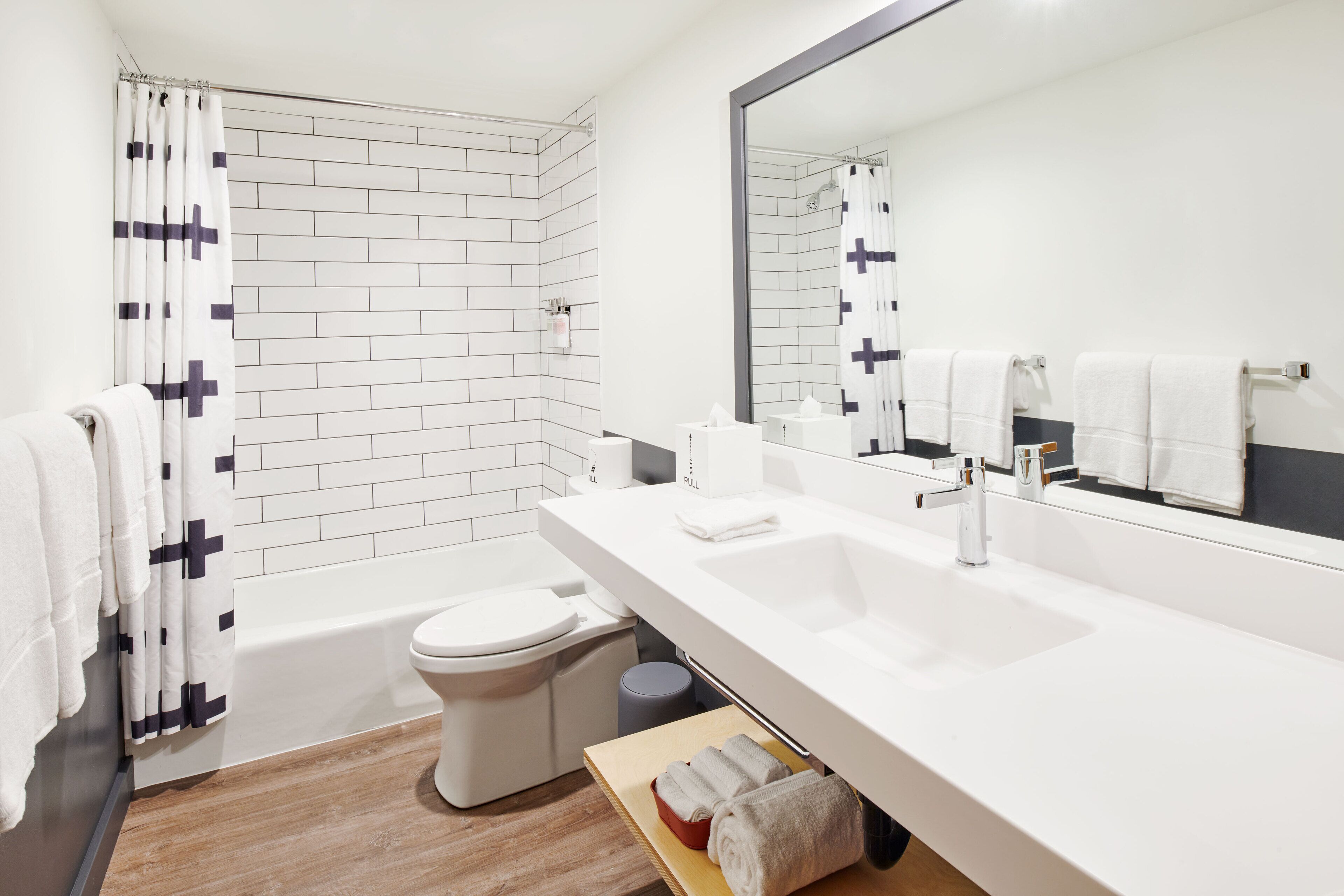 Un baño moderno con lavamanos, espejo y azulejos blancos.