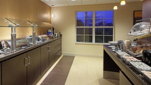 A buffet area with glass display cases, a window with a view of trees, and a tiled floor. - Residence Inn by Marriott Austin Parmer/Tech Ridge (Austin)
