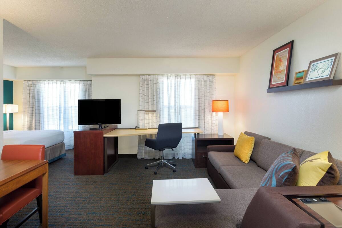 Een hotelkamer met een bed, bureau, stoel, bank en televisie.