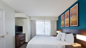Een hotelkamer met een bed, een televisie op een dressoir, een nachtkastje met een lamp en een telefoon.