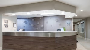 Een receptiebalie met een modern ontwerp, met een grijze muur met ronde patronen en een houten basis.