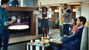 Een moderne woonkamer met een flatscreen televisie, een salontafel met lekkernijen, en een zithoek met een bank en fauteuils.
