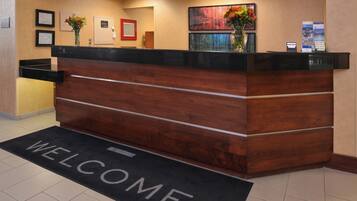 A reception desk with a 'WELCOME' mat in front.