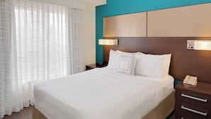 Une chambre d’hôtel avec un grand lit, une table de chevet avec un téléphone et un luminaire fixé au mur.