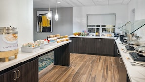 A modern breakfast bar with a variety of food options, including cereal and beverages, in a clean and well-lit room with wooden flooring and a large window. - Residence Inn by Marriott Greenville-Spartanburg Airport (Greenville)