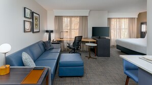 A hotel room with a blue sofa, a desk with a chair, a bed, and a TV. - Residence Inn by Marriott Greenville-Spartanburg Airport (Greenville)