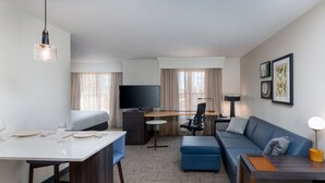 A modern hotel room with a flat-screen TV, a dining table with chairs, a sofa, a desk, and a lamp. - Residence Inn by Marriott Greenville-Spartanburg Airport (Greenville)