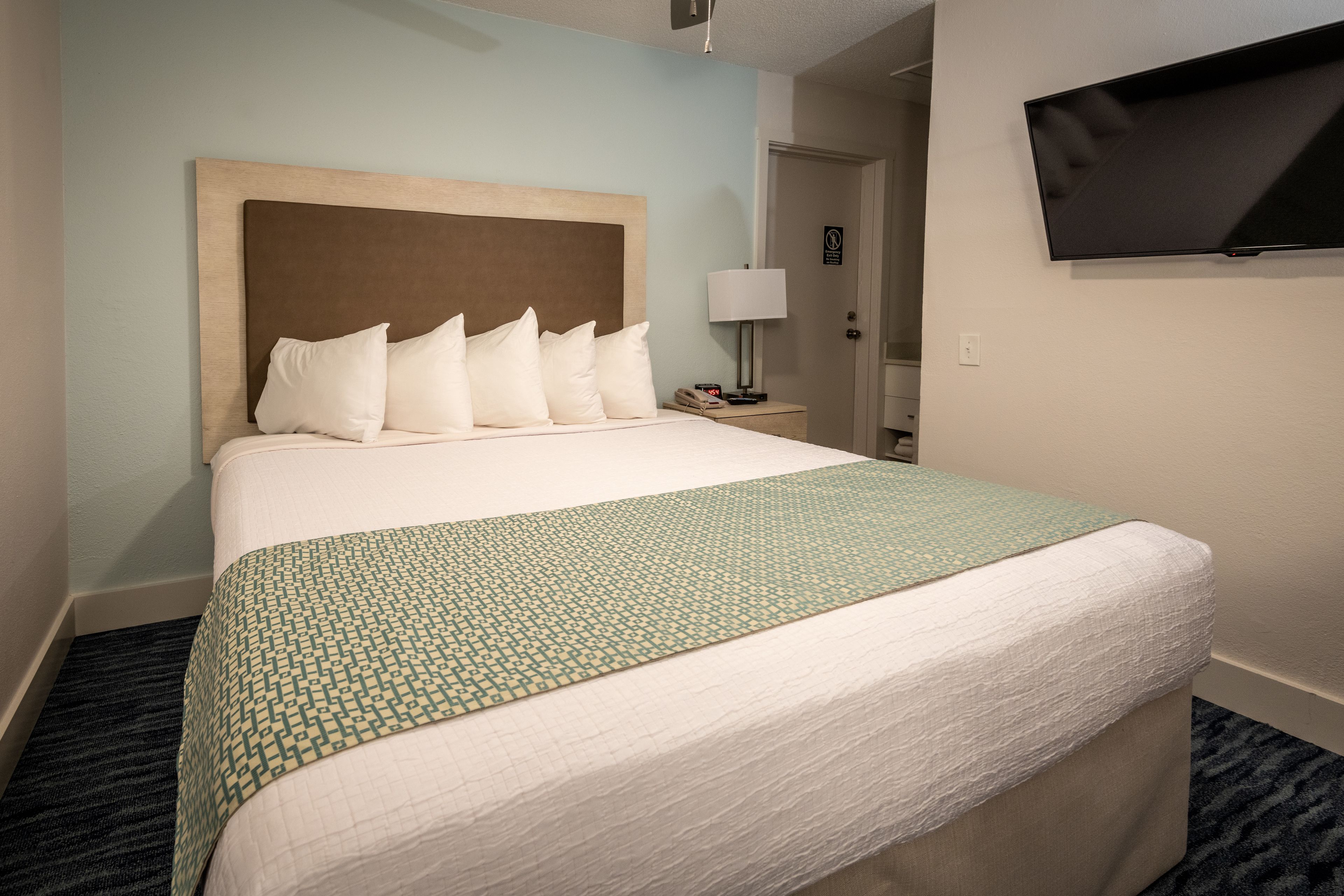 Een hotelkamer met een groot bed, een flatscreen televisie aan de wand en een nachtkastje met een lamp.