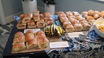 A buffet table with various sandwiches and pickles.