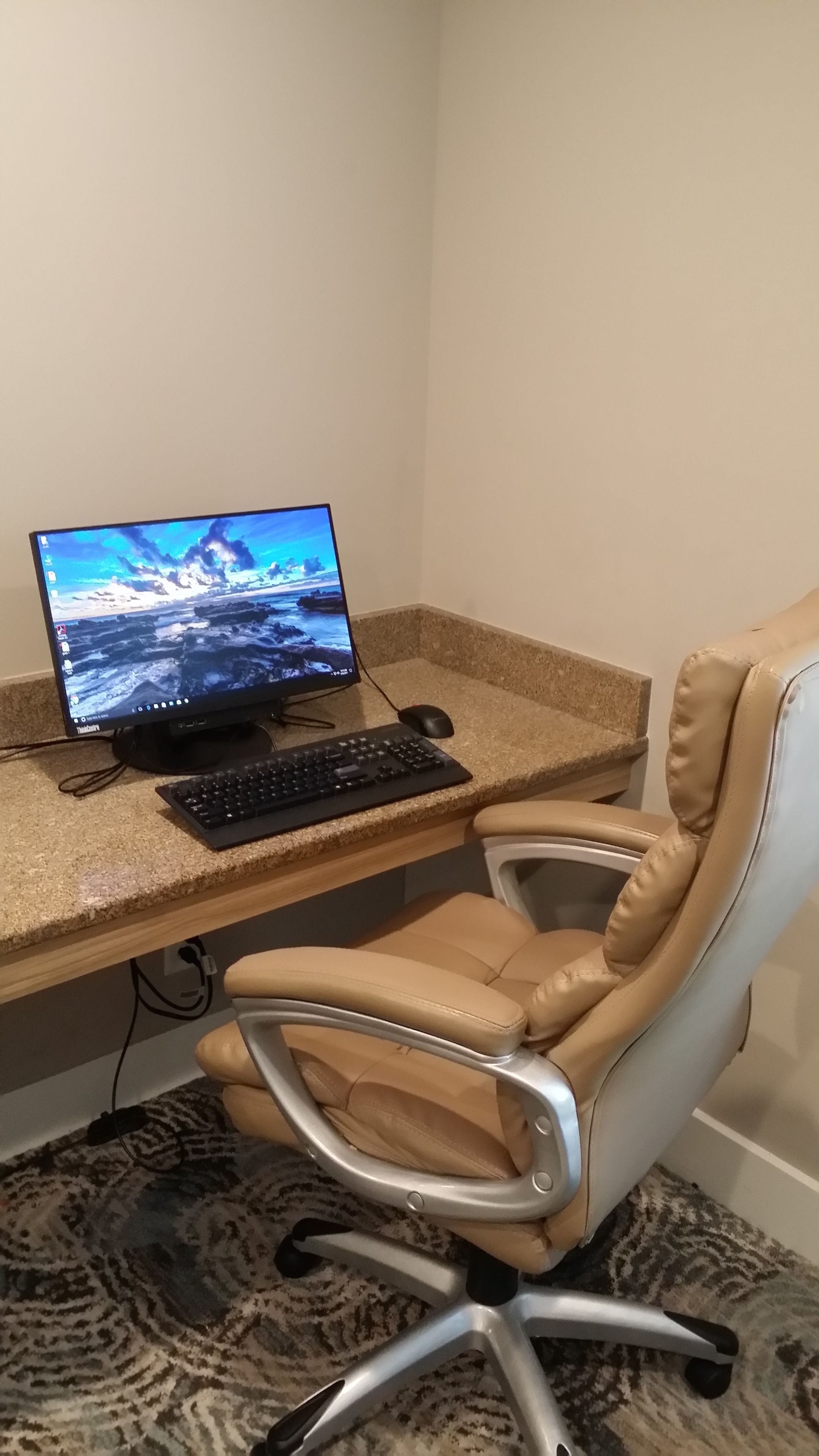 Un espace de travail équipé d’un ordinateur de bureau, d’un clavier, d’une souris et d’un fauteuil de bureau en cuir.