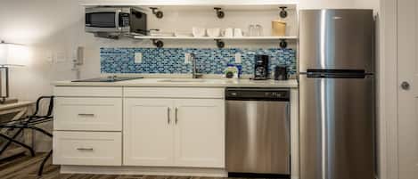 A modern kitchen with white cabinets, a stainless steel refrigerator, a microwave, and a coffee maker.