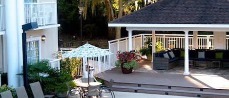 A pool area with lounge chairs, a covered seating area, and a potted plant.