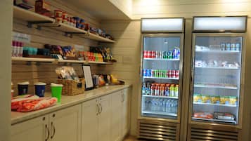 A store with shelves stocked with snacks, beverages, and packaged goods. There are two refrigerated display cases with drinks and snacks.