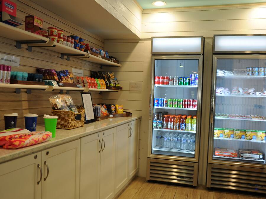 A store with shelves stocked with snacks, beverages, and packaged goods. There are two refrigerated display cases with drinks and snacks.