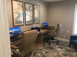 Ein Homeoffice mit zwei Schreibtischen, jeweils mit einem Computer und einem Stuhl ausgestattet. An der Wand befinden sich gerahmte Karten.