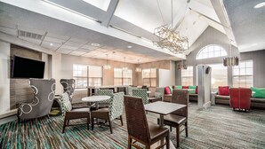 A spacious hotel lobby with high ceilings, large windows, and a variety of seating options including tables, chairs, and sofas. - Residence Inn by Marriott McAllen (McAllen)
