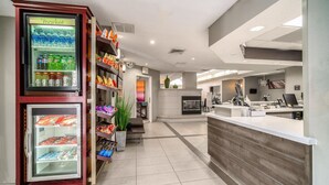 A modern reception area with a refrigerated display case, a counter, and a seating area with a plant. - Residence Inn by Marriott McAllen (McAllen)