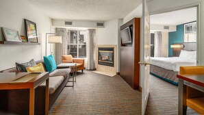 A hotel room with a sofa, a small table, a TV, a fireplace, and a bed. - Residence Inn by Marriott McAllen (McAllen)