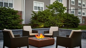 An outdoor seating area with a square fire pit surrounded by wicker chairs. - Residence Inn by Marriott Rochester West/Greece (Rochester)