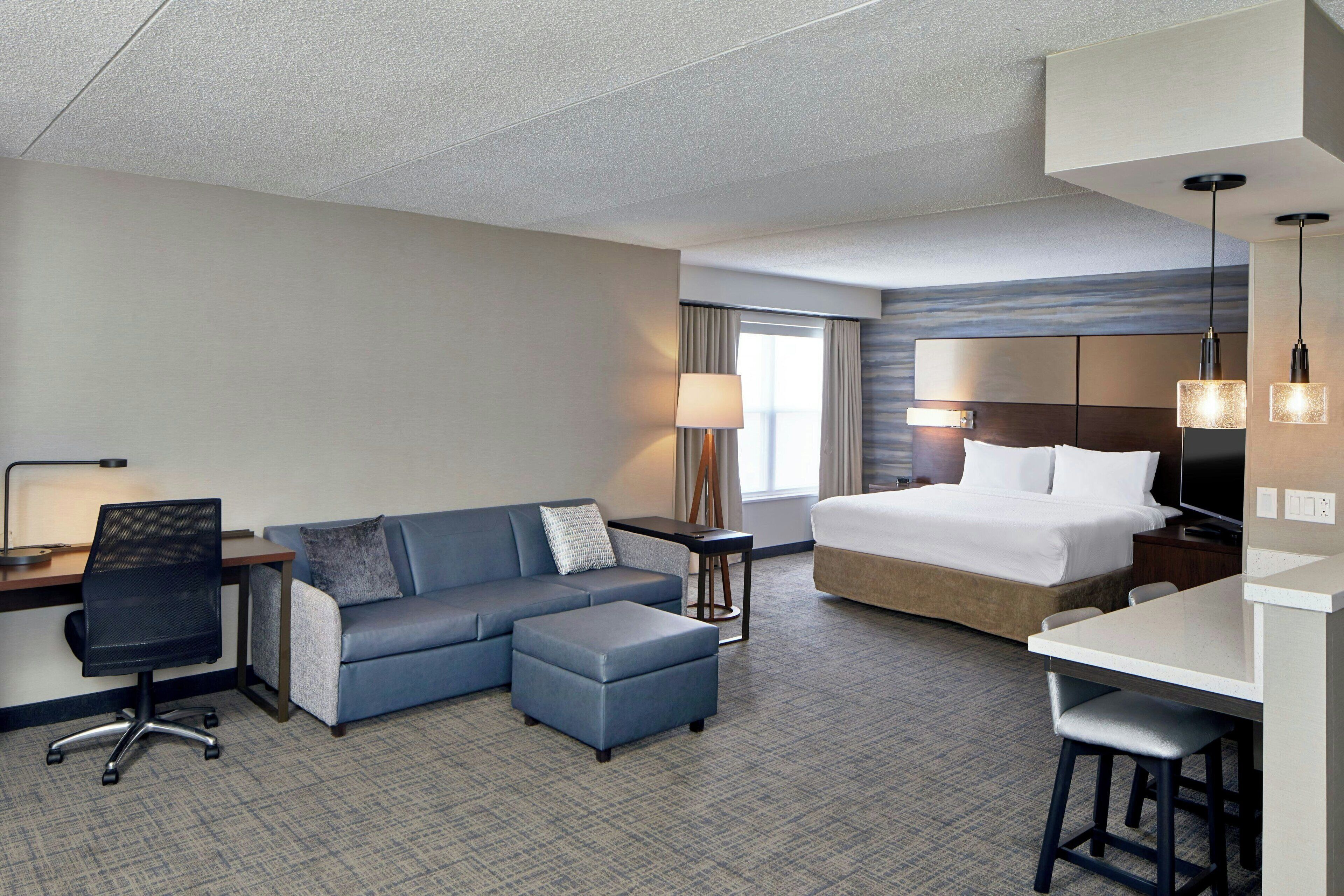 A hotel room with a bed, a sofa, a desk, and a chair.