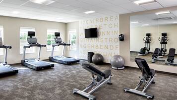 A gym with treadmills, a bench press, and exercise balls.