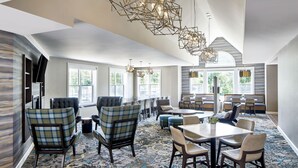A spacious hotel lobby with modern furniture, large windows, and a patterned carpet. - Residence Inn by Marriott Rochester West/Greece (Rochester)