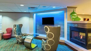 A modern lounge area with a flat-screen TV, a fireplace, and uniquely designed chairs. - Residence Inn By Marriott Louisville Northeast (Louisville)