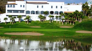 A golf course with a pond, palm trees, and a white building with arched windows. - Real del Mar Hotel & Golf Resort (Tijuana)