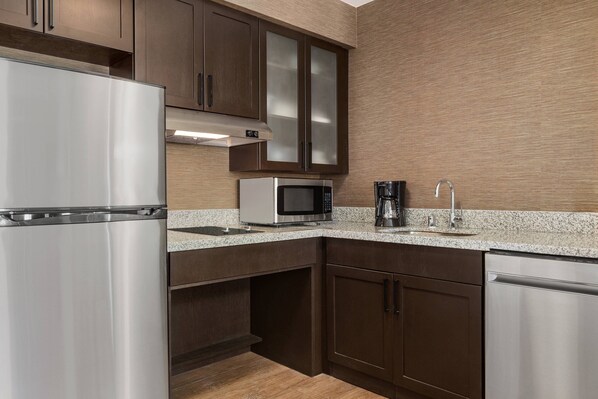 A modern kitchen with stainless steel appliances, dark wooden cabinets, and a granite countertop.