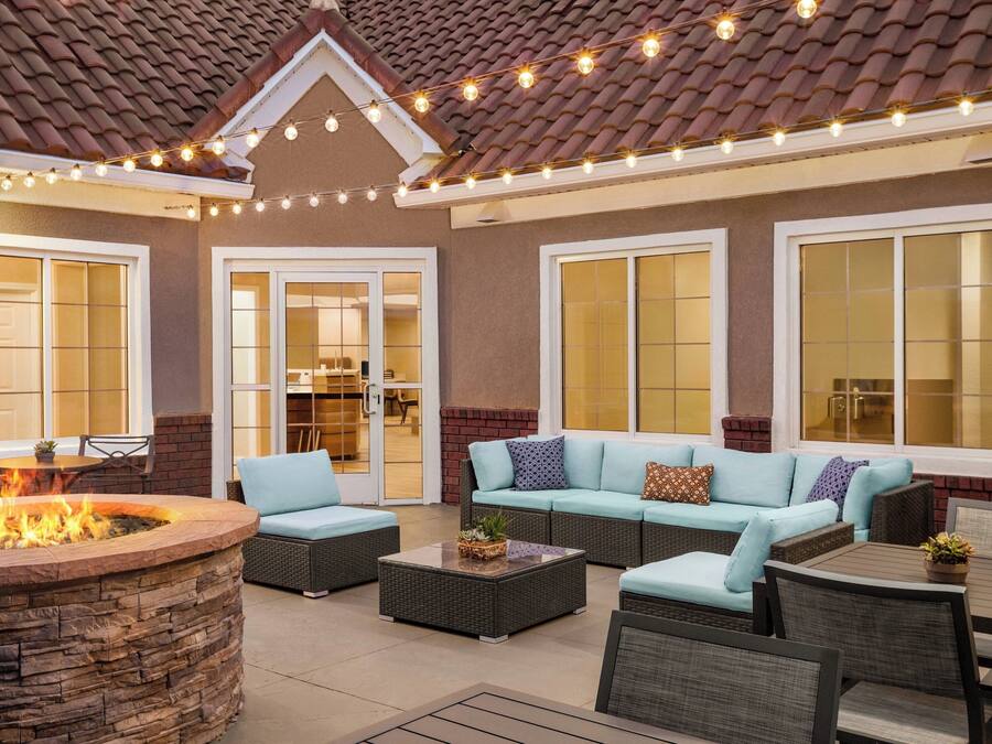 An outdoor patio with a fire pit, seating area, and string lights.