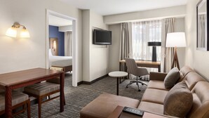 Une chambre d’hôtel avec un lit, un bureau, un canapé, une télévision et une lampe.