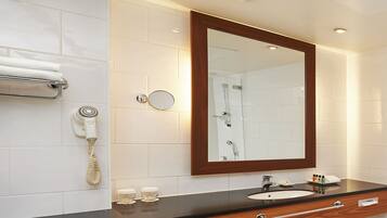 Un baño moderno con tocador de madera, un espejo, un secador de pelo y un perchero para toallas.