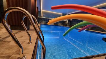 A swimming pool with a metal ladder and colorful floating tubes.