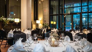 A restaurant with round tables set for dining, each with white tablecloths, silverware, and wine glasses.