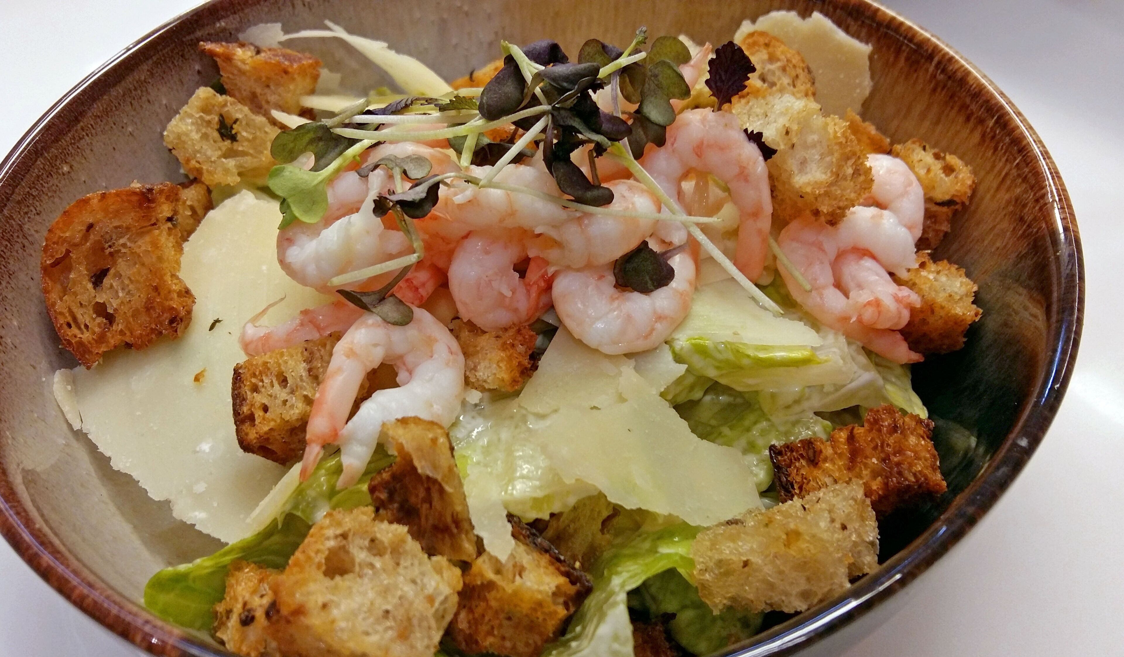 Ensalada con camarones, croutons y hojas verdes.