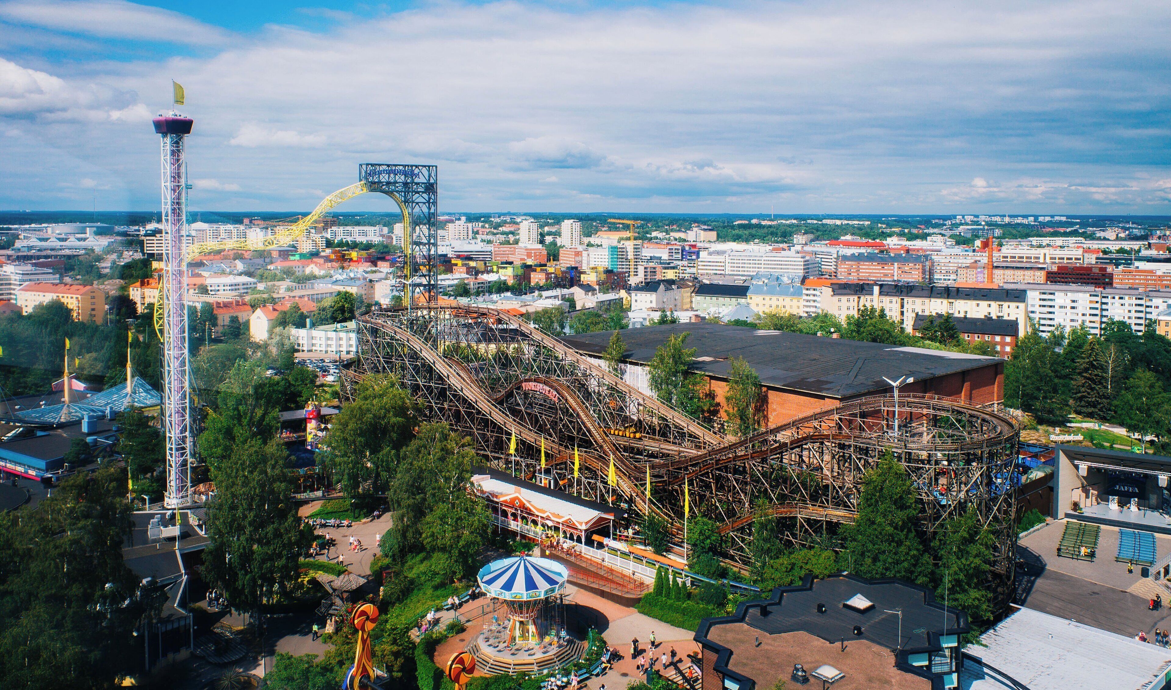 A roller coaster with a loop, surrounded by a park area with a carousel and a tall observation tower.