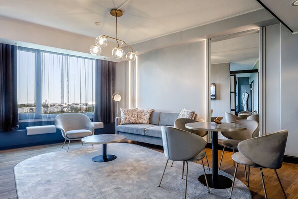 Una sala moderna con un sofá, sillones, una mesa de centro y una mesa de comedor.