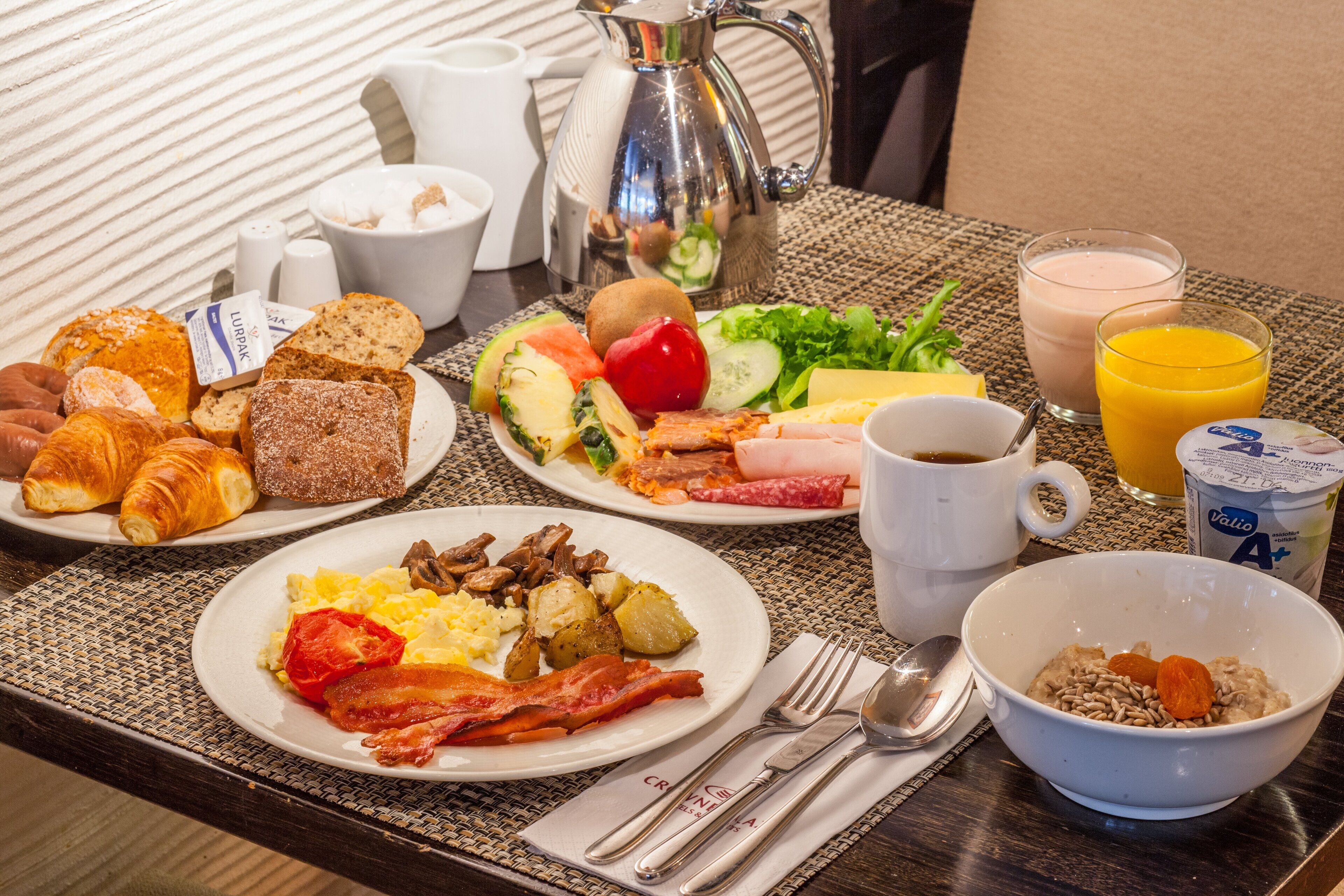 A breakfast buffet with various food items, including croissants, eggs, bacon, and fresh fruits.