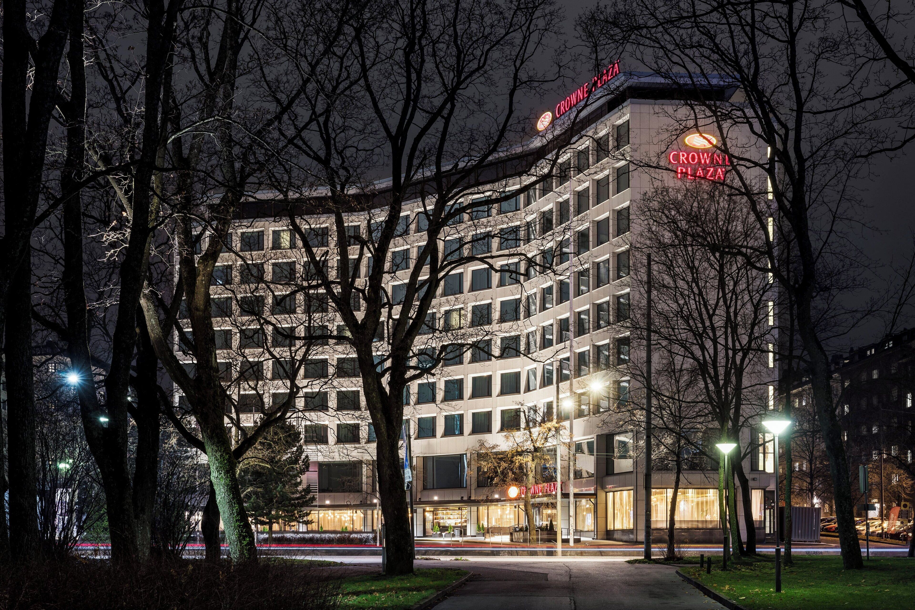 A multi-story hotel with a prominent 'CROWNE PLAZA' sign, surrounded by trees and street lights.