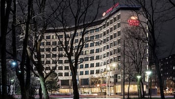 A multi-story hotel with a prominent 'CROWNE PLAZA' sign, surrounded by trees and street lights.
