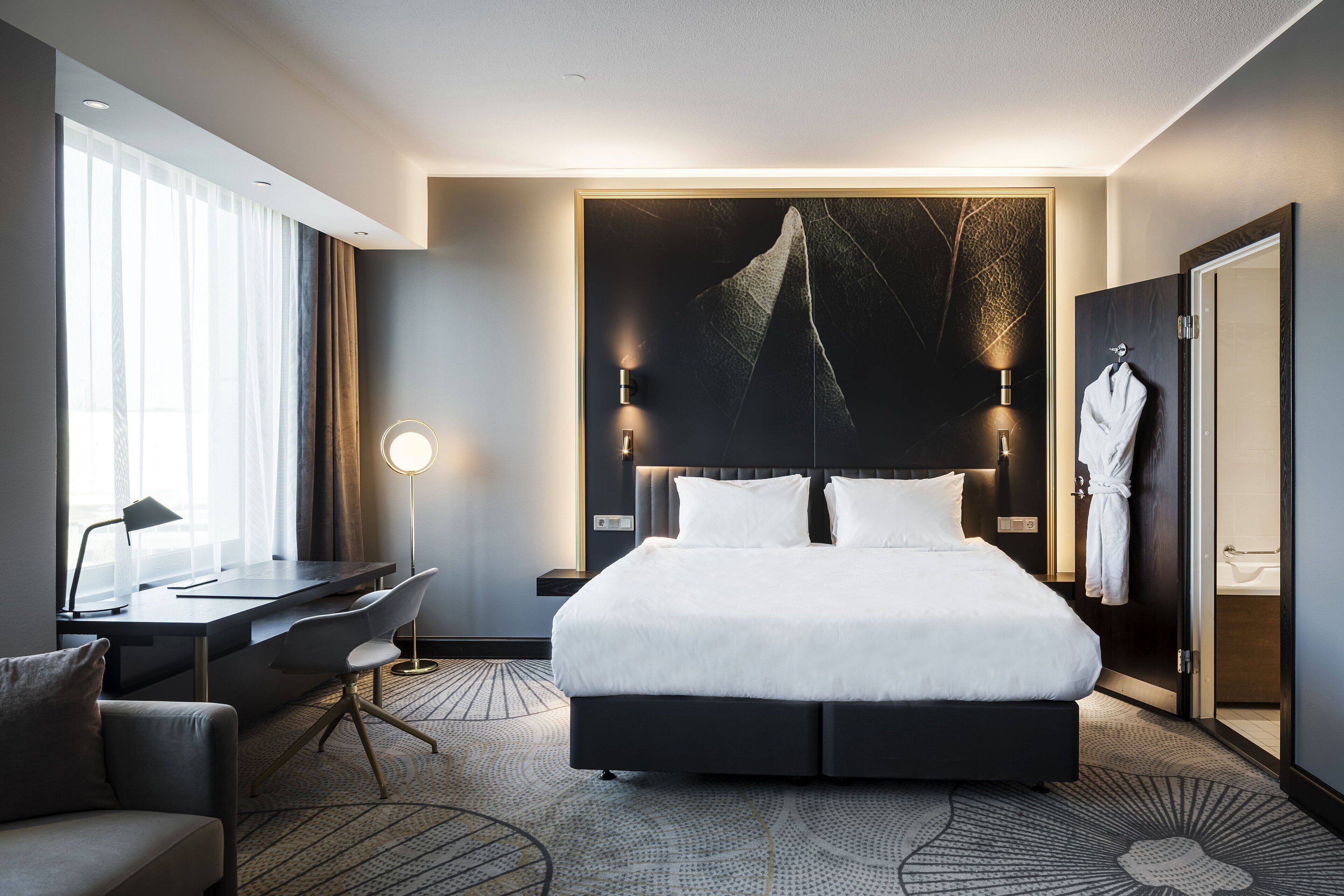 Una habitación de hotel moderna con una cama grande, un escritorio y una silla.