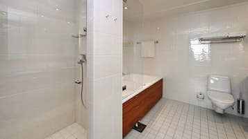 Une salle de bain moderne avec une douche à l’italienne, un meuble-lavabo en bois, des toilettes blanches et une baignoire entourée de parois en verre.