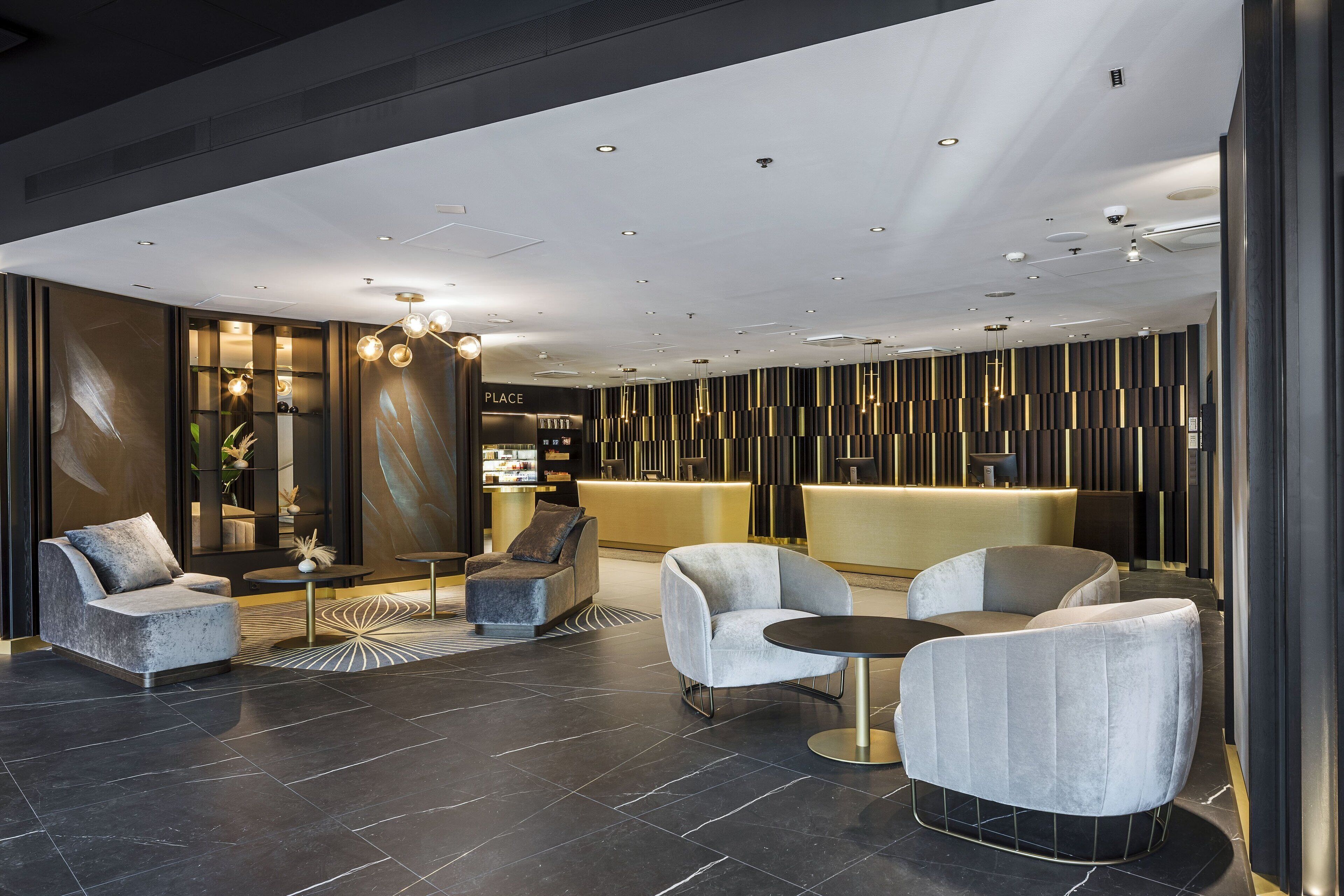A modern lobby with dark flooring, contemporary seating, and a reception area with vertical light panels.